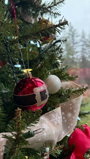 A Santa-belt ornament nestled in pine with snowflake ribbon
